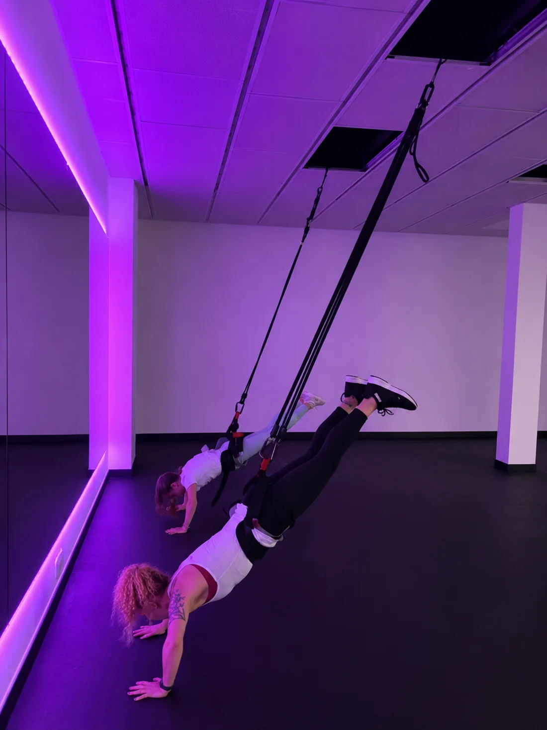 Bungee fitness class at RBF Studio — members flying in harnesses under purple lights